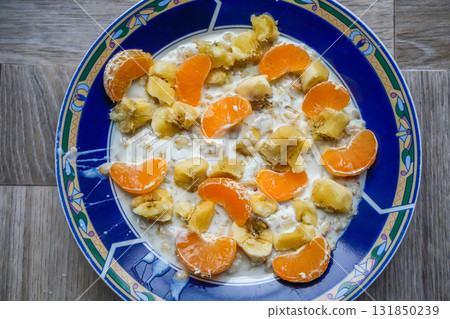 Oatmeal breakfast with banana and mandarin on blue plate 131850239