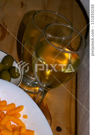 Glass of ehite wine , and green olives , on the table 131850288