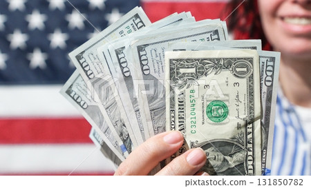 American Financial Prosperity Hand Holding Dollar Bills Against USA Flag Backdrop American Financial Prosperity Hand Holding Dollar Bills Against USA Flag Backdrop 131850782