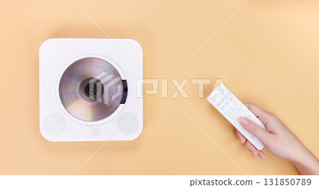 Modern White CD Player with Remote Control on Beige Background, Minimalist Audio Device Modern White CD Player with Remote Control on Beige Background, Minimalist Audio Device 131850789