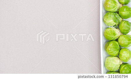 Raw organic Brussel sprouts on white plate on grey background, top view. Flat lay, overhead, from above. Copy space. Raw organic Brussel sprouts on white plate on grey background, top view. Flat lay, overhead, from above. Copy space. 131850794