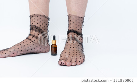 Sore, heavy legs and tired feet in sheer polka dot stockings beside a small amber bottle, illustrating the concept of relaxation and self-care Sore, heavy legs and tired feet in sheer polka dot stockings beside a small amber bottle, illustrating the concept of relaxation and self-care 131850905