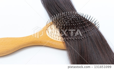 Healthy hair being brushed with a wooden hairbrush, showcasing smooth strands and the importance of hair care and maintenance for vibrant locks Healthy hair being brushed with a wooden hairbrush, showcasing smooth strands and the importance of hair care and maintenance for vibrant locks 131851099
