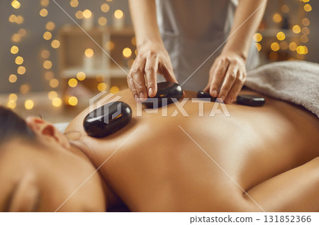 Young woman having hot stone massage in spa salon 131852366