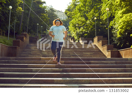 Overweight fat woman jogging in the summer city park and having sport training outdoors. Overweight fat woman jogging in the summer city park and having sport training outdoors. 131853002