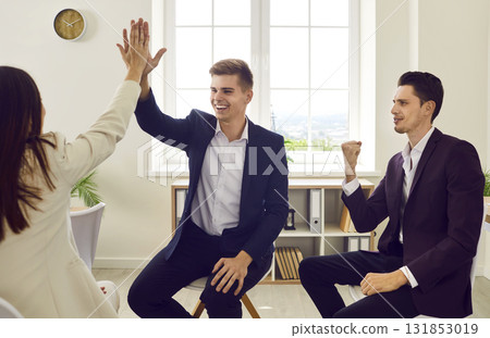 Business people sitting in office and making deal. Man giving high five to woman finishing meeting 131853019