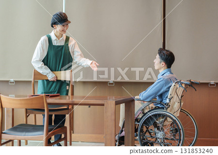 咖啡館工作人員引導一位坐輪椅的男子 咖啡館工作人員引導一位坐輪椅的男子 131853240