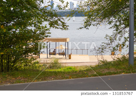 Urban waterfront by the lake with gazebo and benches, framed by foliage Urban waterfront by the lake with gazebo and benches, framed by foliage 131853767