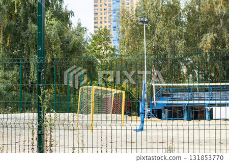 Beach sports court behind green fence goal and volleyball posts horizontal photo 131853770