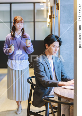 A woman bringing coffee to a male colleague in an office 131853932