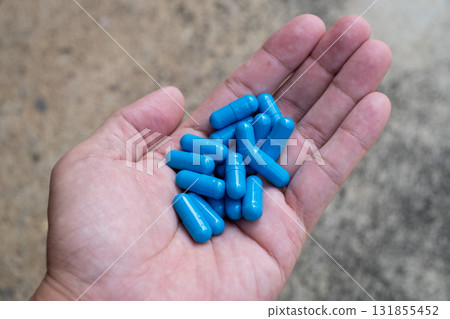 Close-up of a hand holding multiple blue capsules Close-up of a hand holding multiple blue capsules 131855452