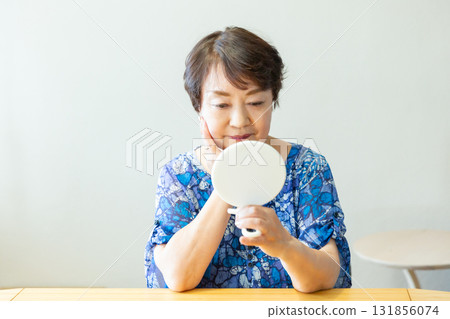 一位老年婦女用手鏡看著自己的臉 131856074