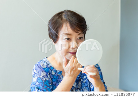 一位老年婦女用手鏡看著自己的臉 131856077