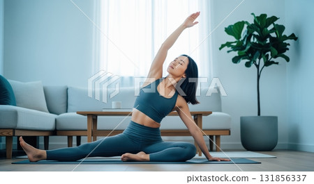 Young asian woman practicing yoga side bend stretch in a bright minimalist living room Young asian woman practicing yoga side bend stretch in a bright minimalist living room 131856337