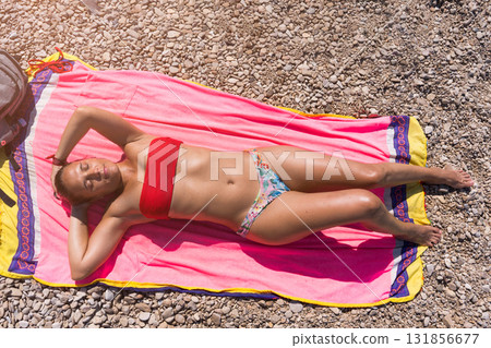 Woman relaxing sunbathing on pebble beach in Croatia Woman relaxing sunbathing on pebble beach in Croatia 131856677