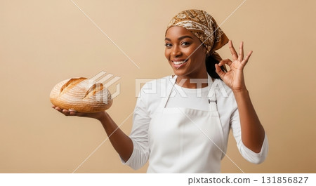 Smiling african american female baker holding fresh bread and showing perfect sign 131856827