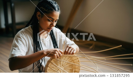 Skilled woman with braided hair meticulously weaving a natural rattan basket by hand 131857295