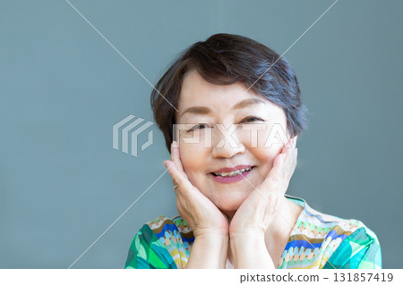 Senior woman smiling with a relaxed expression, hands on cheeks, upper body 131857419