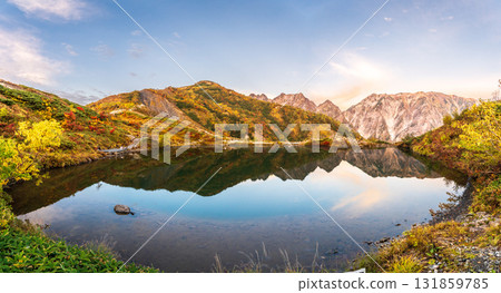 Autumn leaves of the Hakuba Sanzan mountains reflected in Happoike Pond at dawn 131859785