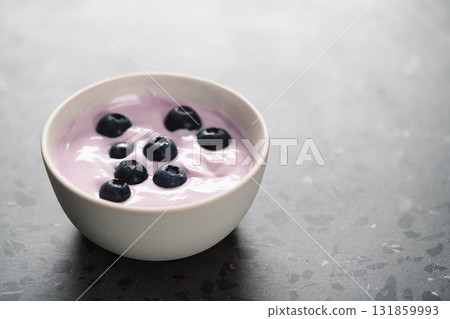 Blueberry yogurt with whole berries in white bowl on concrete background 131859993