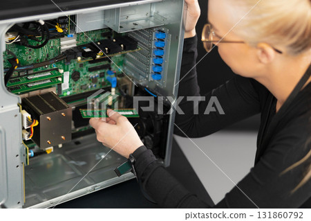 Female IT technician upgrades and repairs server hardware inside a rack-mounted computer system 131860792