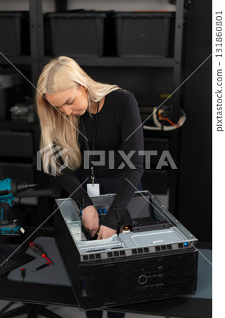 Female IT technician in a data center upgrading and maintaining a server chassis 131860801