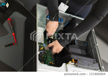 Adult male IT technician performing server hardware upgrade inside a computer rack during maintenance 131860804
