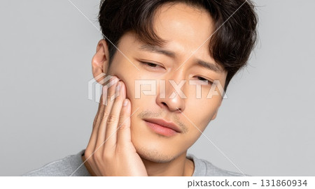 Close up of young Korean man holding his cheek in pain during a dental toothache moment 131860934