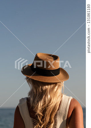 Woman hat ocean, enjoying summer vacation view from behind on beach with clear sky copy space Woman hat ocean, enjoying summer vacation view from behind on beach with clear sky copy space 131861180
