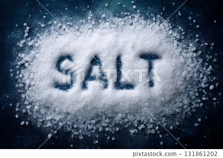 Overhead view of coarse white salt crystals completely covering background with the word salt spelled clearly 131861202