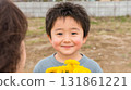 Smiling young Japanese boy presenting vibrant bouquet of flowers to delighted mother 131861221