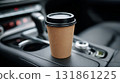 Takeaway coffee cup placed in open center console cup holder inside modern vehicle interior 131861225