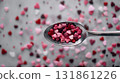 Top down perspective showing silver spoon filled with pink and red heart shapes on white background 131861226