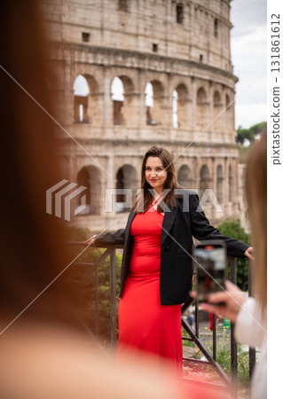Woman in red dress and black blazer posing near Colosseum in Rome Woman in red dress and black blazer posing near Colosseum in Rome 131861612