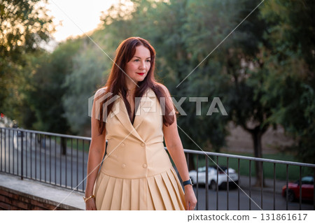 Elegant woman in beige dress walking on terrace at sunset 131861617