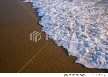 Gentle waves wash over golden sand during sunset on a tranquil beach in a coastal location, creating a serene environment for relaxation and reflection Gentle waves wash over golden sand during sunset on a tranquil beach in a coastal location, creating a serene environment for relaxation and reflection 131862437