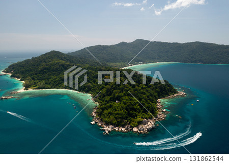Aerial view of the Perhentian Islands in Malaysia. Serene view of the coast with lush green hills and clear blue waters on a sunny day in a tropical location Aerial view of the Perhentian Islands in Malaysia. Serene view of the coast with lush green hills and clear blue waters on a sunny day in a tropical location 131862544