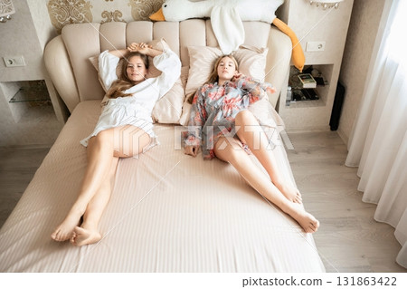Women Bedroom Relaxing Bed: Two young women relaxing on a bed in a bedroom, likely for leisure or rest. Women Bedroom Relaxing Bed: Two young women relaxing on a bed in a bedroom, likely for leisure or rest. 131863422