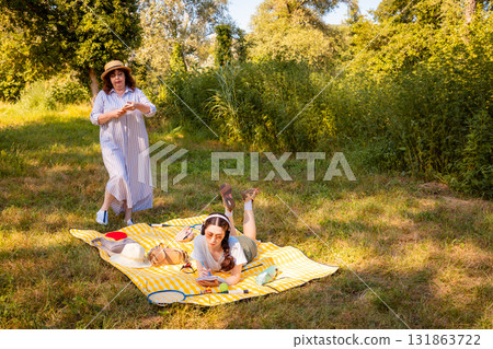 Mother and young daughter enjoying quality time together in nature. Picnic, relaxation, and emotional health. Wide shot Mother and young daughter enjoying quality time together in nature. Picnic, relaxation, and emotional health. Wide shot 131863722