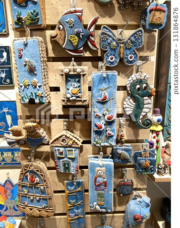 Colorful ceramic wall art featuring animals and nature on wooden display at artisan market Colorful ceramic wall art featuring animals and nature on wooden display at artisan market 131864876