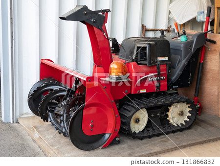 A red snowplow placed in a garage 131866832