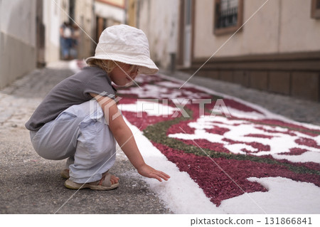 Girl looking at a traditional colorful carpet in Portugal during a Catholic festival Girl looking at a traditional colorful carpet in Portugal during a Catholic festival 131866841