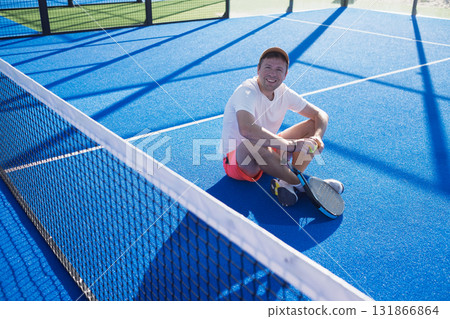 European man sitting on the padel court resting after the game 131866864