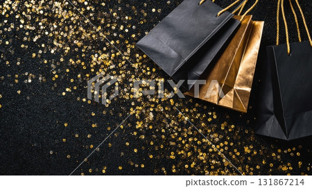 Fashion flat lay with black and gold shopping bags and sparkling golden confetti on black background 131867214