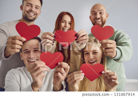 Happy smiling group of young people friends holding red hearts in hands on gray background. 131867914