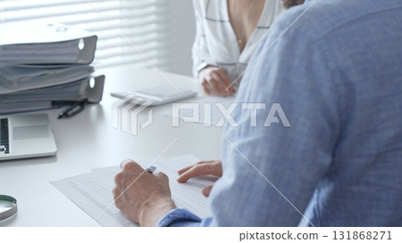 Professional team collaborating, reviewing financial reports, using calculator, analyzing data while working at sleek corporate workspace. Audit and taxes in business 131868271