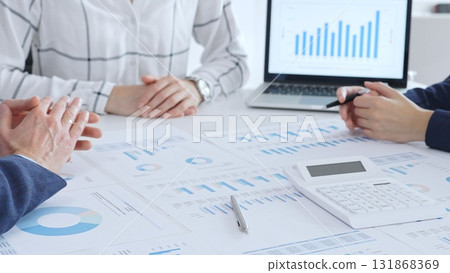 Business people discussing financial data and analyzing market trends during a corporate meeting, reviewing strategy with charts and graphs in the office Business people discussing financial data and analyzing market trends during a corporate meeting, reviewing strategy with charts and graphs in the office 131868369
