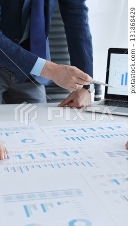 Business professionals analyzing financial data and market trends during a corporate meeting, collaborating on reports and developing strategic investment plans Business professionals analyzing financial data and market trends during a corporate meeting, collaborating on reports and developing strategic investment plans 131868429