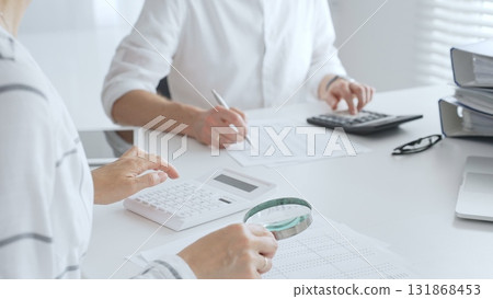 Groupe of accountants collaborating on financial analysis, using a magnifying glass, calculator, and laptop to ensure data accuracy. Audit and taxes Groupe of accountants collaborating on financial analysis, using a magnifying glass, calculator, and laptop to ensure data accuracy. Audit and taxes 131868453