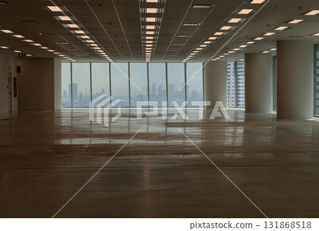 A large, empty room with a panoramic city skyline view through floor-to-ceiling windows. 131868518